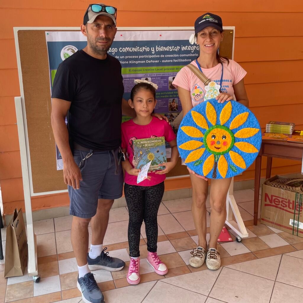 father, daughter, and teacher holding sunflower art