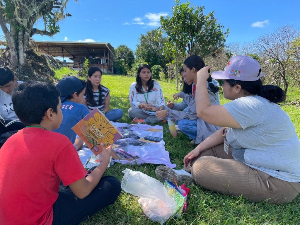 group of children sitting in a circle on grass discussing La Mision de Letty book